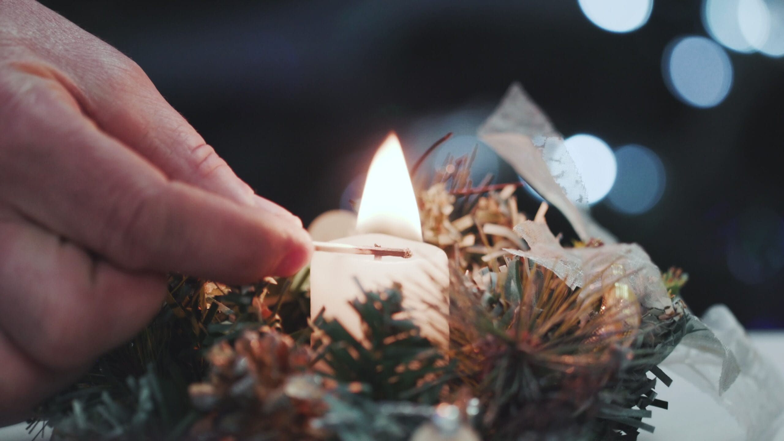 Manos encendiendo una vela en memoria de un ser querido durante las fiestas navideñas