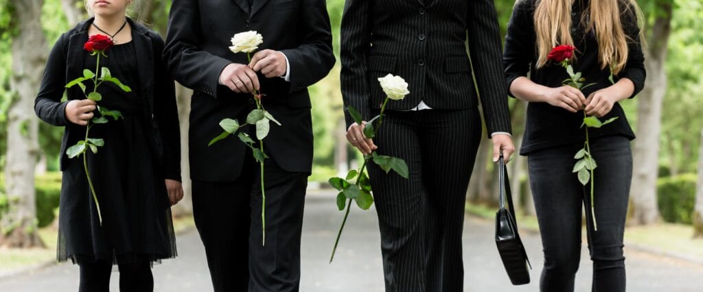 Hombres y mujeres con vestimenta sobria caminando hacia una ceremonia al aire libre